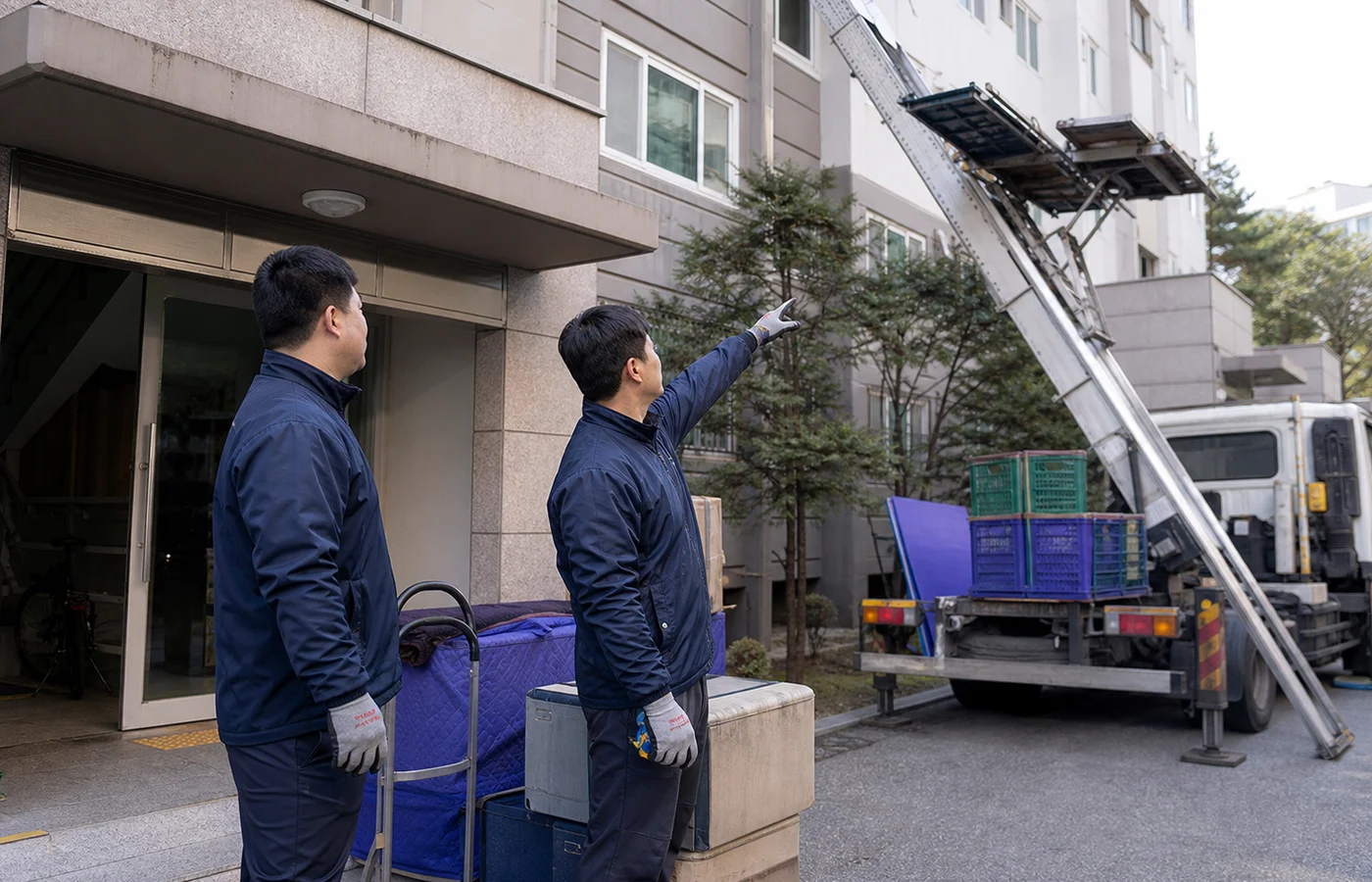 한국 아파트 앞에서 이삿짐 운반 동선을 확인하는 작업자